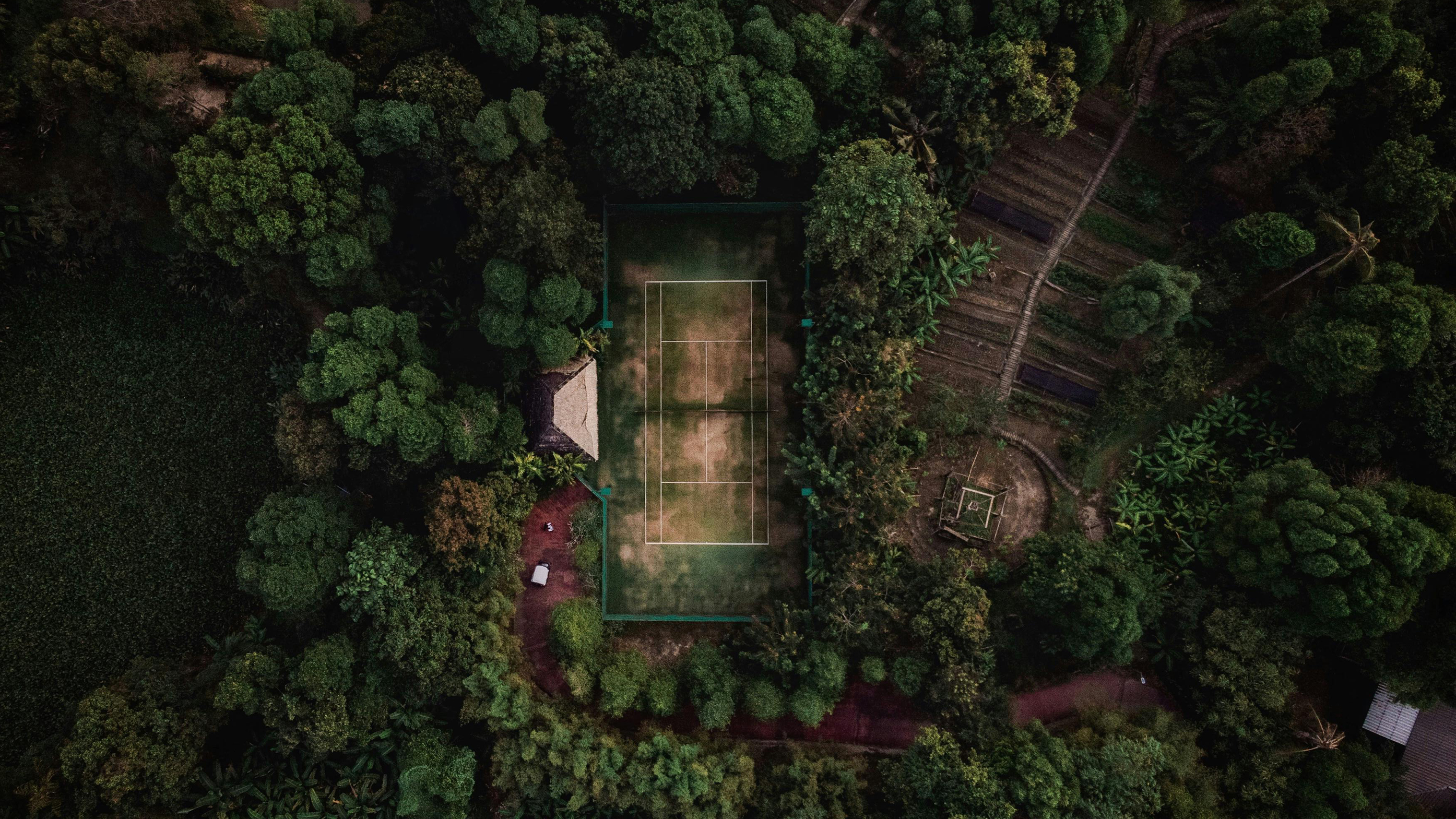 Aerial view of a tennis court surrounded by lush tropical forest